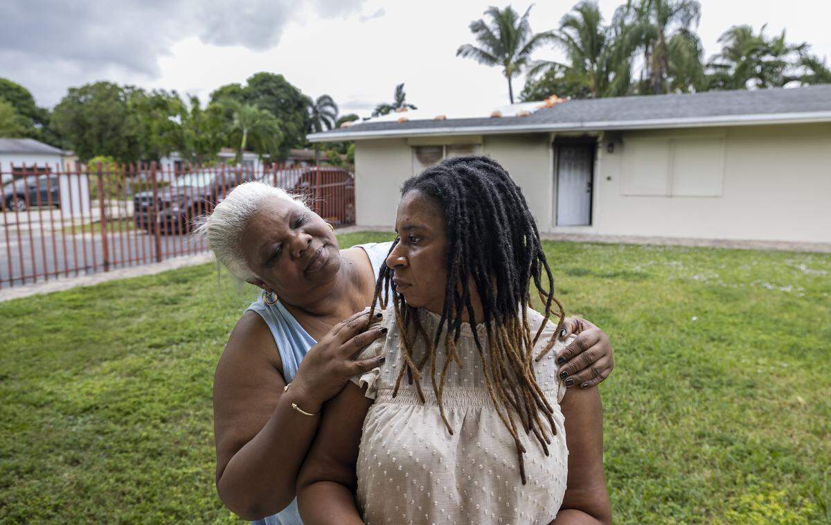 Pauline Dufresne is consoled by her neighbor, Barbara Francis, outside of her home on Wednesday, Nov. 5, 2025, in Miami, Fla. Dufresne, a Haitian TPS holder, lost her home to a fire in July and, without insurance, has been left without power, running water or a place to live. She and her four children are temporarily staying with a nearby neighbor.