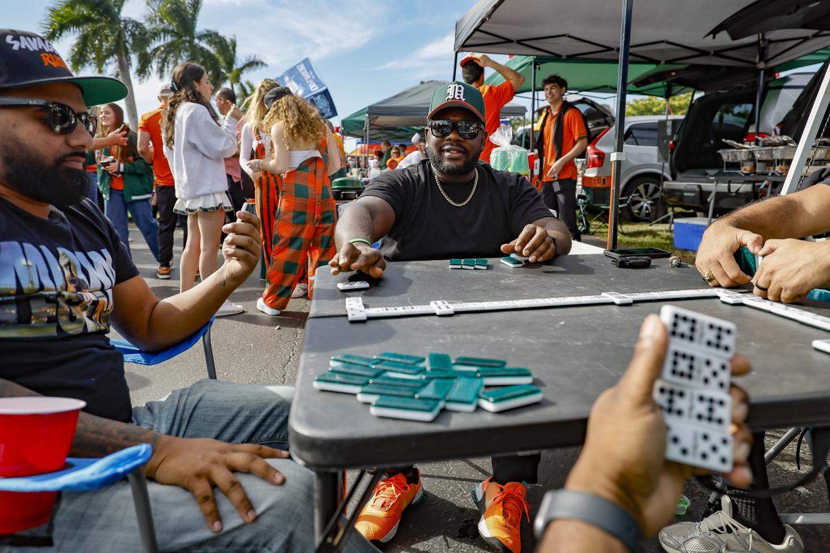 Frankie Hosein of Pembroke Pines and Terrell Ross of Hollywood, left to right, play dominoes during the tail gate parties before the College Football Playoff National Championship Game between the Miami Hurricanes and the Indiana Hoosiers at Hard Rock Stadium in Miami Gardens, Florida, on Monday, January 19, 2026.