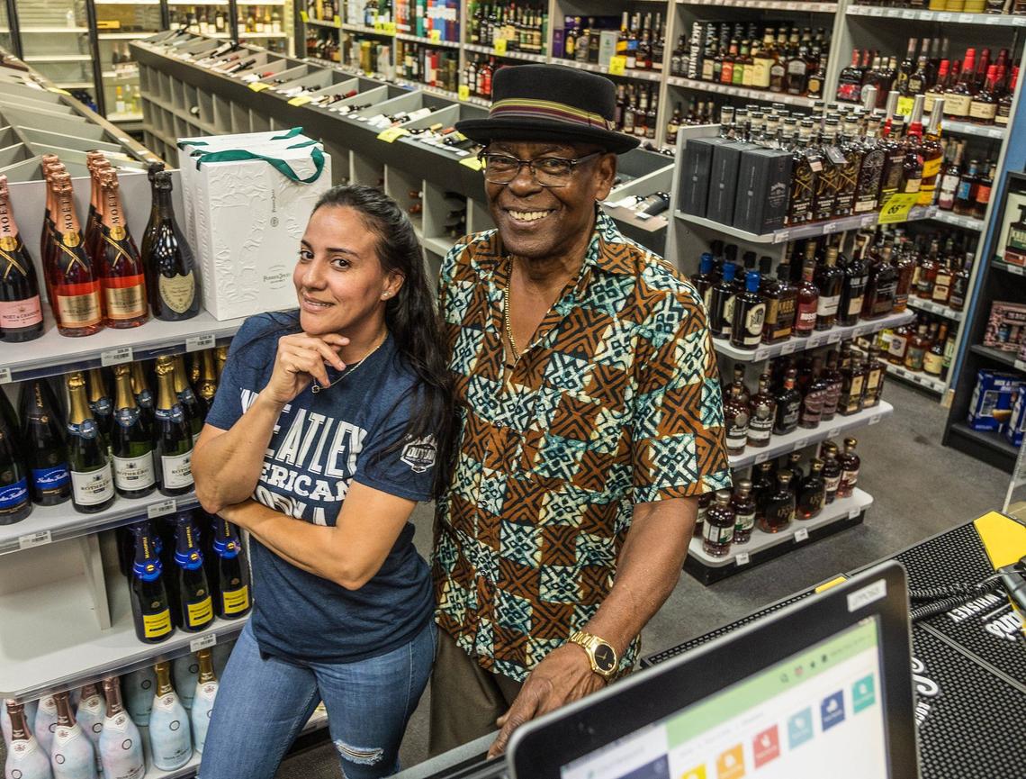 Jensen’s at Sunset Corners’ cashier Soribel Duran poses with John McGriff who has worked at this wine and spirits shop on Sunset Drive and Galloway Road for 49 years. He will continue working at the landmark family business for the new owners, he said. They are seen here on June 7, 2024.