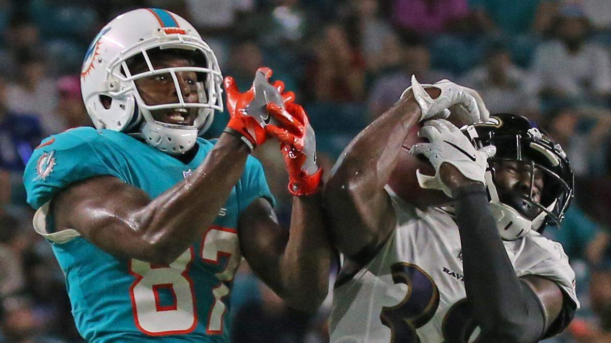 Baltimore Ravens cornerback Stanley Jean-Baptiste intercepts the ball against Miami Dolphins wide receiver Rashawn Scott during third quarter of an NFL preseason football game at Hard Rock Stadium on Saturday, August 25, 2018, in Miami Gardens.
