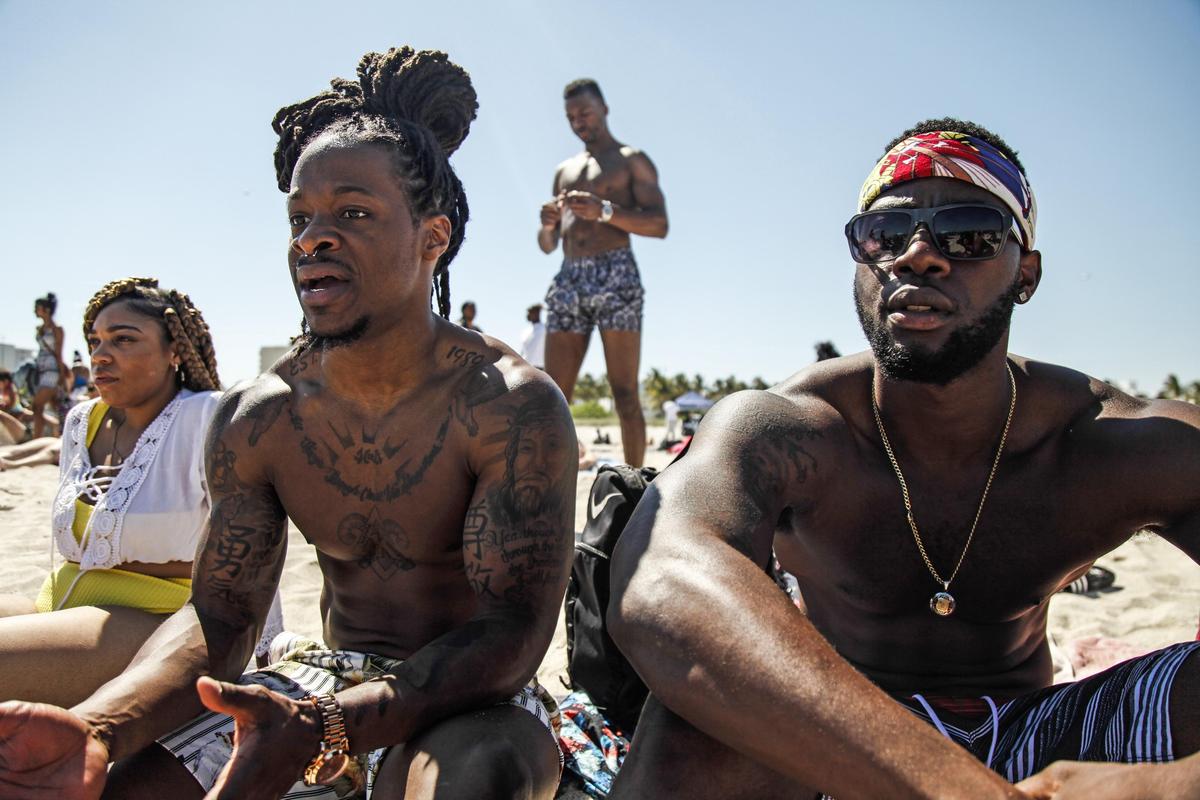 Jerome Haynes (left) and Whisly Laurent lounge on the beach but consider this to be the worst reunion vacation they’ve been on because of the ramped-up policing in South Beach.