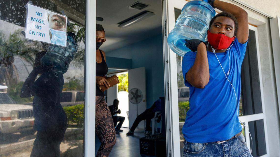 A man carries drinking water for a customer at a water depot store before the arrival of Hurricane Isaias in Freeport, Grand Bahama, Bahamas, Friday, July 31, 2020.