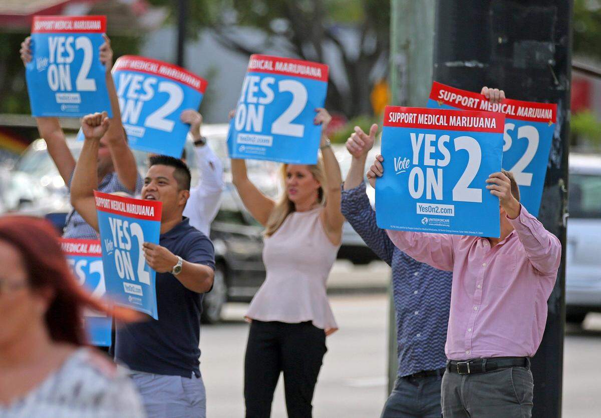 Supporters of Amendment 2 wave signs at passing traffic on the corner of Oakland Park Boulevard and Federal Hightway in Fort Lauderdale on Tuesday, Nov. 8, 2016.