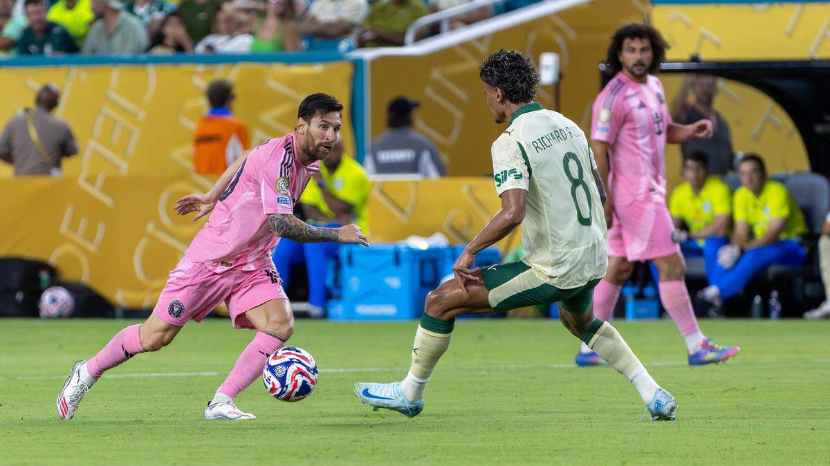 El delantero del Inter Miami, Lionel Messi (izq.), trata de pasar la marca del mediocampista del Palmeiras, Richard Ríos, en el partido del Grupo A del Mundial de Clubes celebrado el 23 de junio de 2024 en el Hard Rock Stadium en Miami Gardens, Florida.