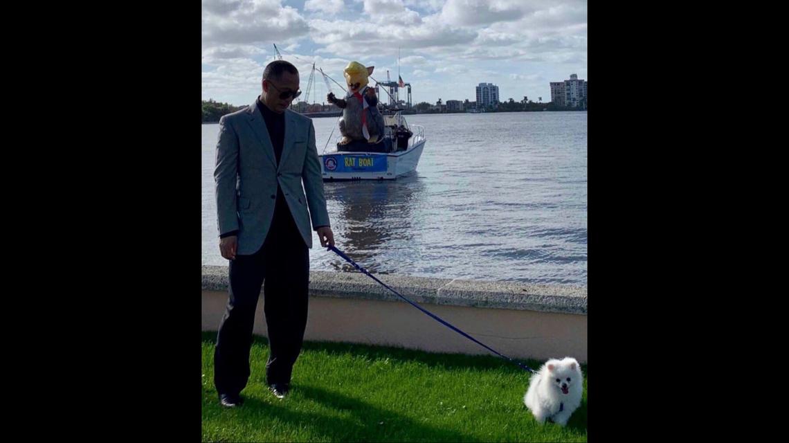 A photo shows Guo Wengui walking his dog outside Mar-a-Lago in late December 2018 as anti-Trump protesters pulled up in a boat behind him.