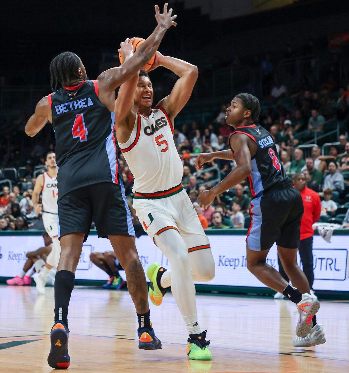 UM froward Malik Reneau threads through Delaware State players Zion Bethea, left, and Jalen St. Clair for the basket as Miami Hurricanes (4-1) played against Delaware State Hornets in the first half at the Watsco Center in Coral Gables, on Sunday, November 23, 2025.