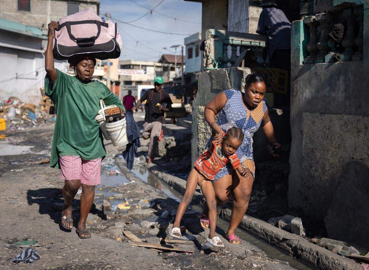 A woman carries a child during a fight between police and gang members in downtown Port-au-Prince.