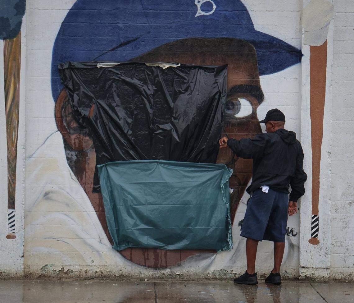 An unidentified Downtown Development Authority personnel takes a close look at the mural of Jackie Robinson, the first black to integrate Major League Baseball in 1947, after it was defaced by someone with a swastika and Jim-Crow era racial epithet on Tuesday, June 3, 2025, at Dorsey Park in Miami, Florida.
