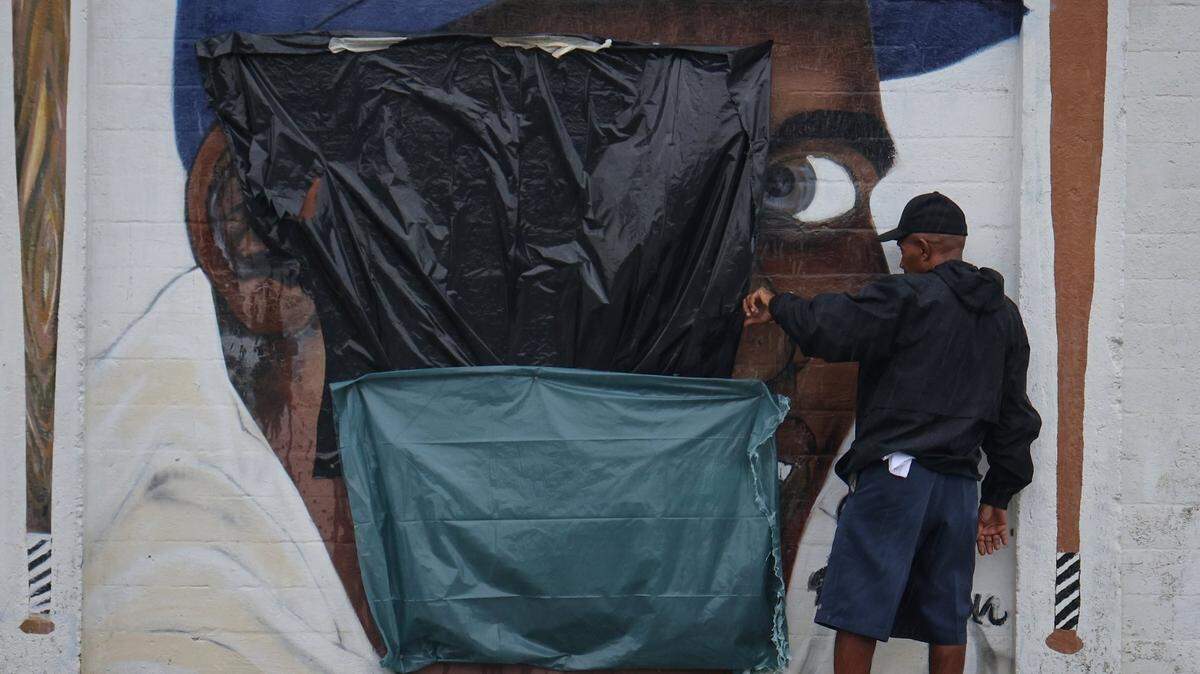 An unidentified Downtown Development Authority personnel takes a close look at the mural of Jackie Robinson, the first black to integrate Major League Baseball in 1947, after it was defaced by someone with a swastika and Jim-Crow era racial epithet on Tuesday, June 3, 2025, at Dorsey Park in Miami, Florida.