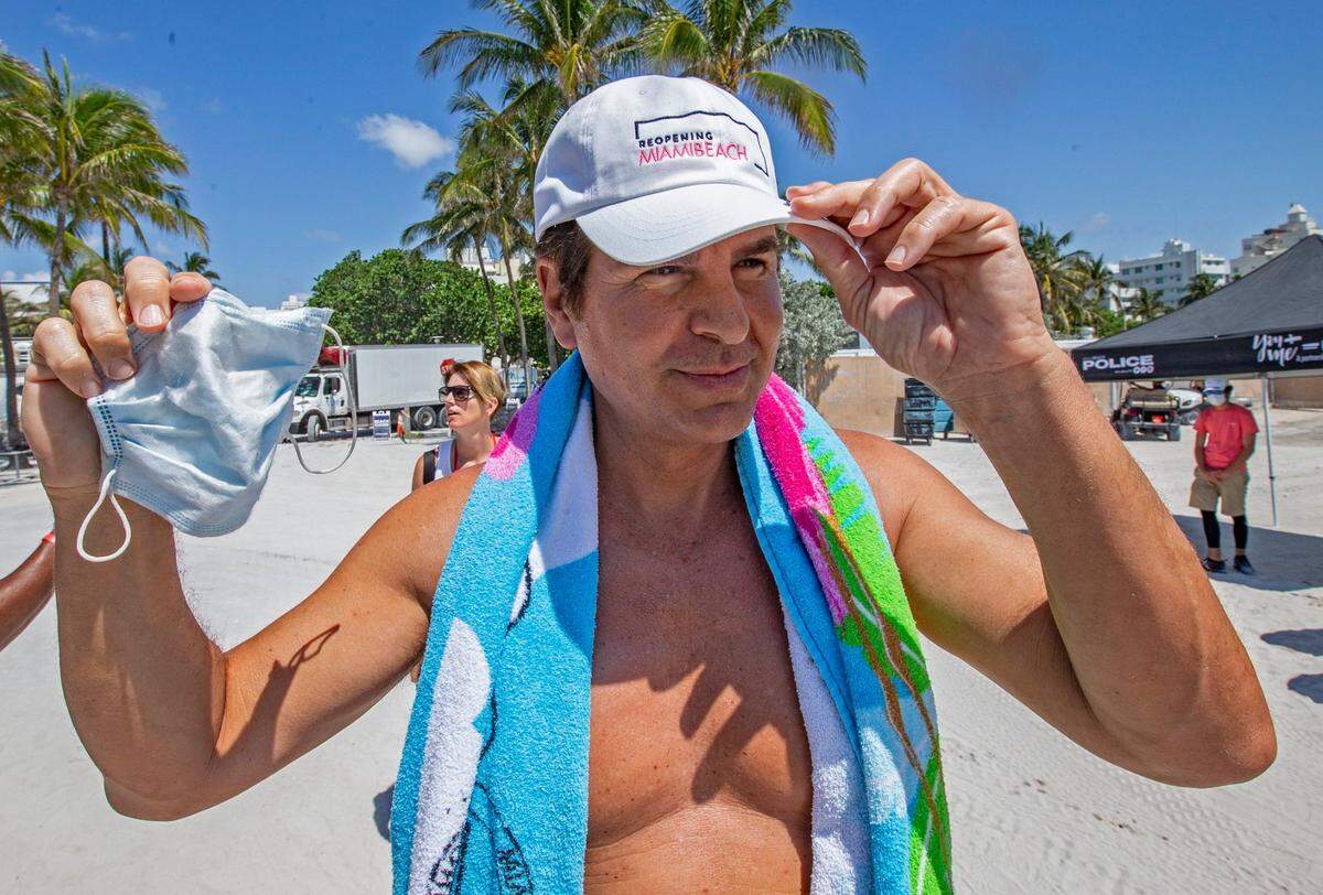 El actor Vincent De Paul se prueba una gorra de reapertura de Miami Beach antes de caminar hacia la playa en Ocean Drive y la calle 10 mientras el condado de MIami-Dade abre playas después del cierre del coronavirus el miércoles 10 de junio de 2020.