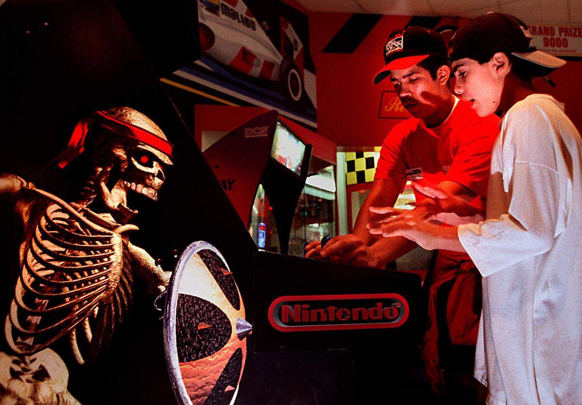 Steve Munoz, 14, right, plays “Killer Instinct” at Malibu Grand Prix with some advice from employee Yako Heredia in this 1995 file photo.