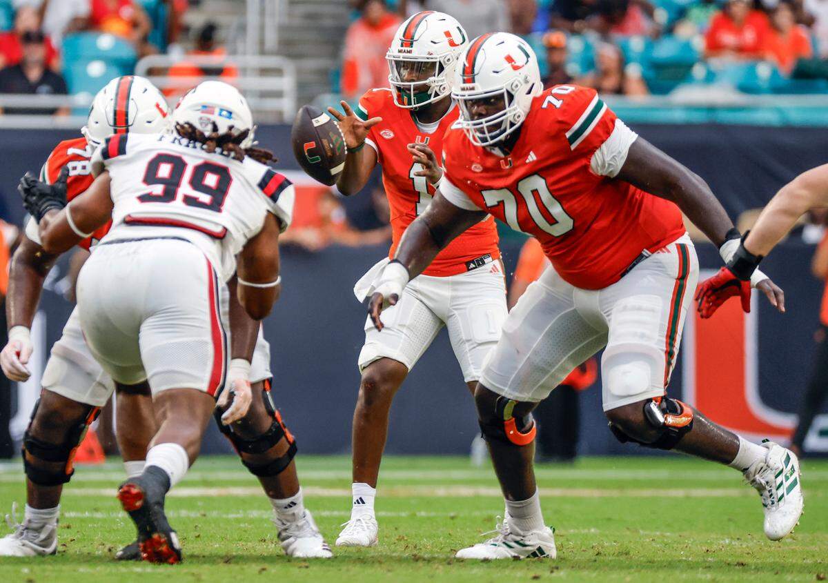Miami Hurricanes offensive lineman Markel Bell (70) blocks Ball State Cardinals defenders as quarterback Cam Ward (1)takes a snap in the first half of an NCAA football game at Hard Rock Stadium in Miami Gardens, Florida on Saturday, September 14, 2024.