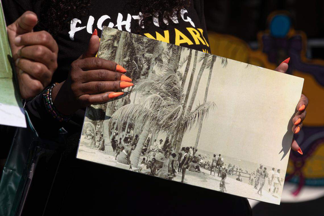 A participant of the symbolic ‘wade-in’ holds an archival image of Historic Virginia Key Beach Park on Saturday, Nov. 12, 2022.