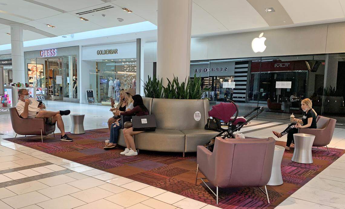 Shoppers take a break at Dadeland Mall. Some guests removed their masks to eat or drink takeout items they’d bought elsewhere in the mall.
