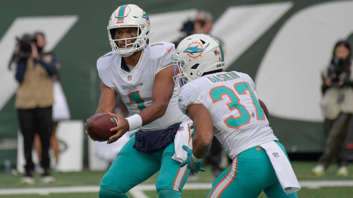 Miami Dolphins quarterback Tua Tagovailoa, left, hands off to Myles Gaskin during the second half of an NFL football game against the New York Jets, Sunday, Nov. 21, 2021, in East Rutherford, N.J. (AP Photo/Bill Kostroun)