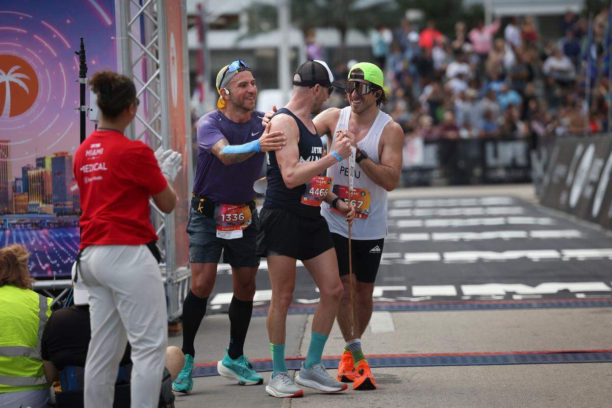 Three runners embrace after crossing the finish line during the Life Time Miami Marathon on Sunday, Jan. 29, 2023, in Miami.
