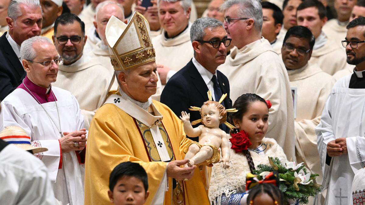 Pope Leo XIV carries the statue of the Baby Jesus at the end of the Christmas Eve mass at St Peter's Basilica in the Vatican on December 24, 2025.