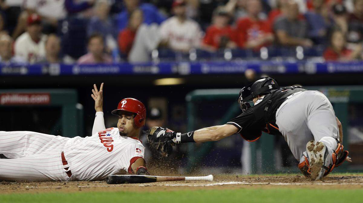 Philadelphia Phillies’ Aaron Altherr, left, slides past Miami Marlins catcher J.T. Realmuto to score on a two-run fielder’s choice hit into by Roman Quinn during the fourth inning of a baseball game, Friday, Sept. 14, 2018, in Philadelphia.