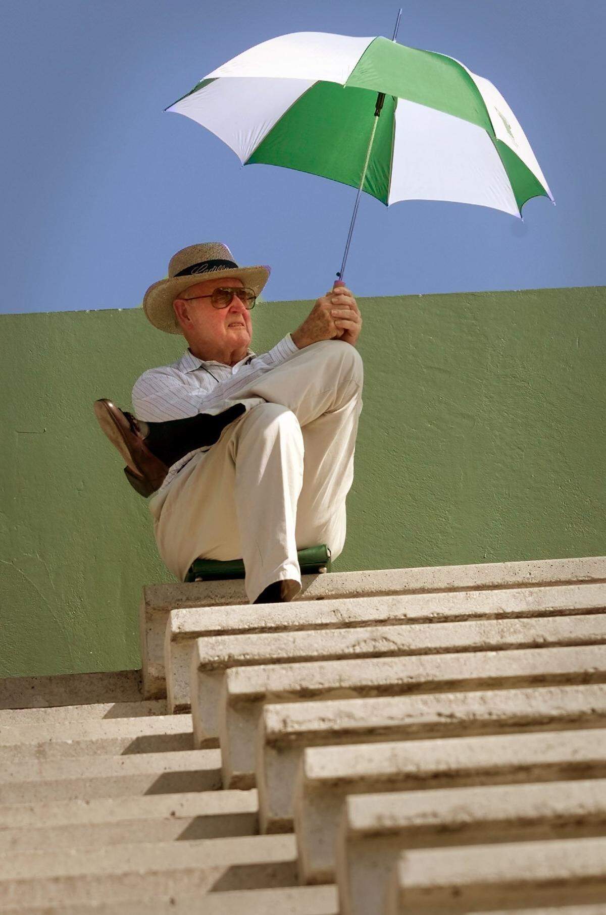 George Corrigan takes shelter from the heat at Mark Light Stadium during the NCAA Regional at the University of Miami's home field in this May 2000 file photo. He was watching Florida International play Florida Atlantic. Corrigan was a 1949 UM graduate.
