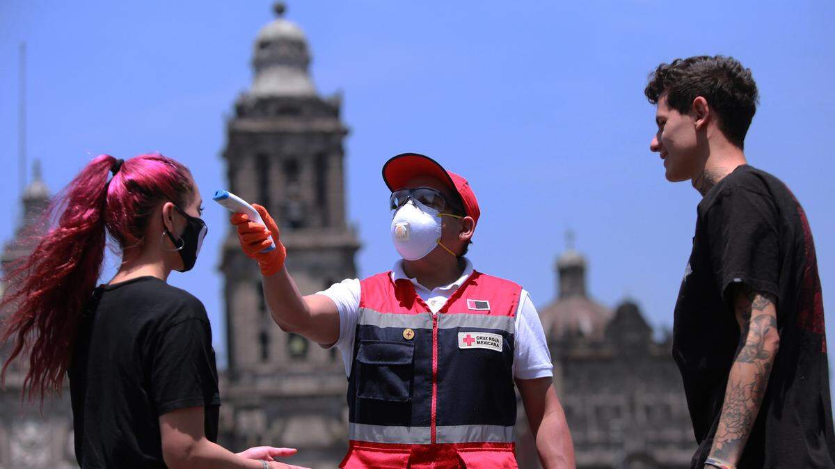 A Red Cross member checks the temperature and puts antibacterial gel on pedestrians in Mexico City, Mexico.