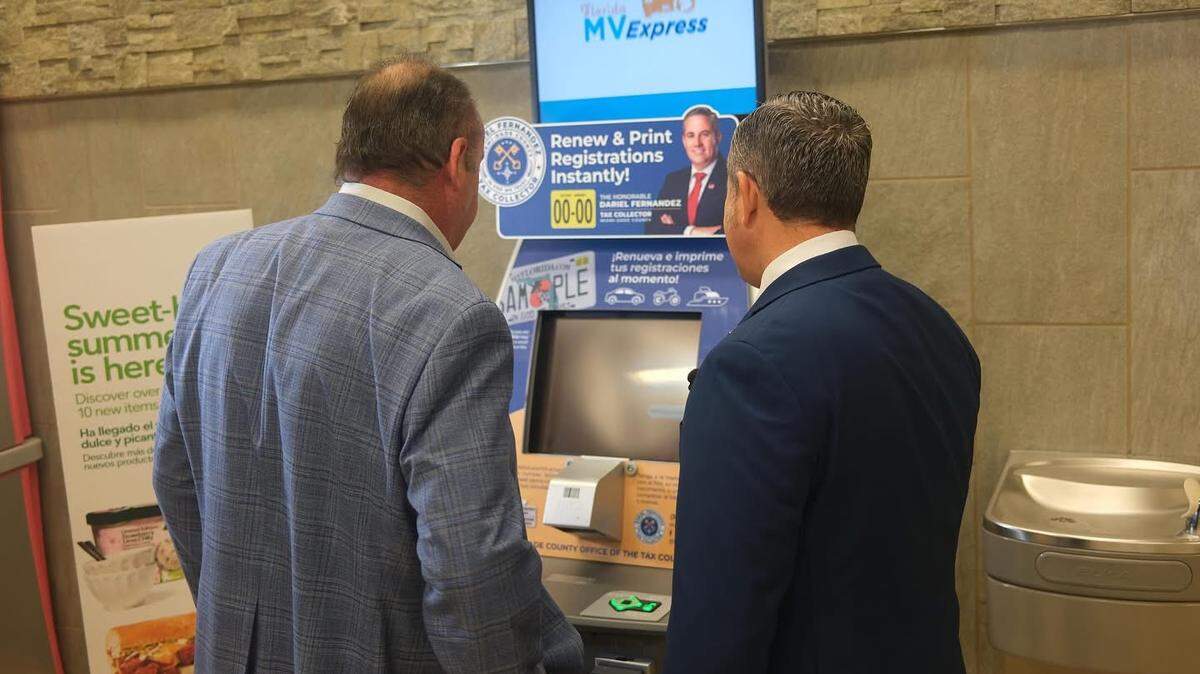 Miami-Dade Tax Collector Dariel Fernández (right) shows how a Florida MV Express self-service kiosk at Publix can be used to renew a driver’s registration at a launch event at the Doral Publix on July 11, 2025.