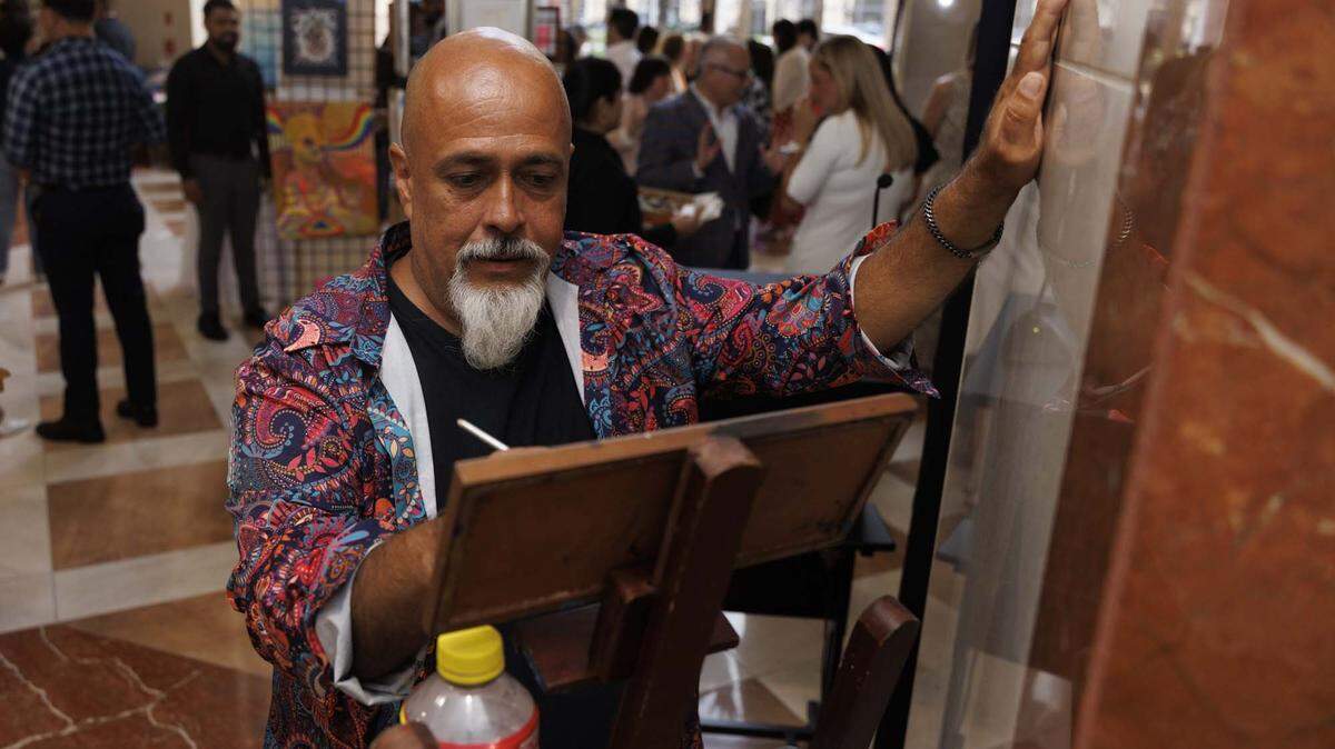 Hernan Lopez, artist name Hernando, paints during the Camillus House art show on Wednesday, May 27, 2026, in the foyer at Amerant Bank in Coral Gables, Fla.