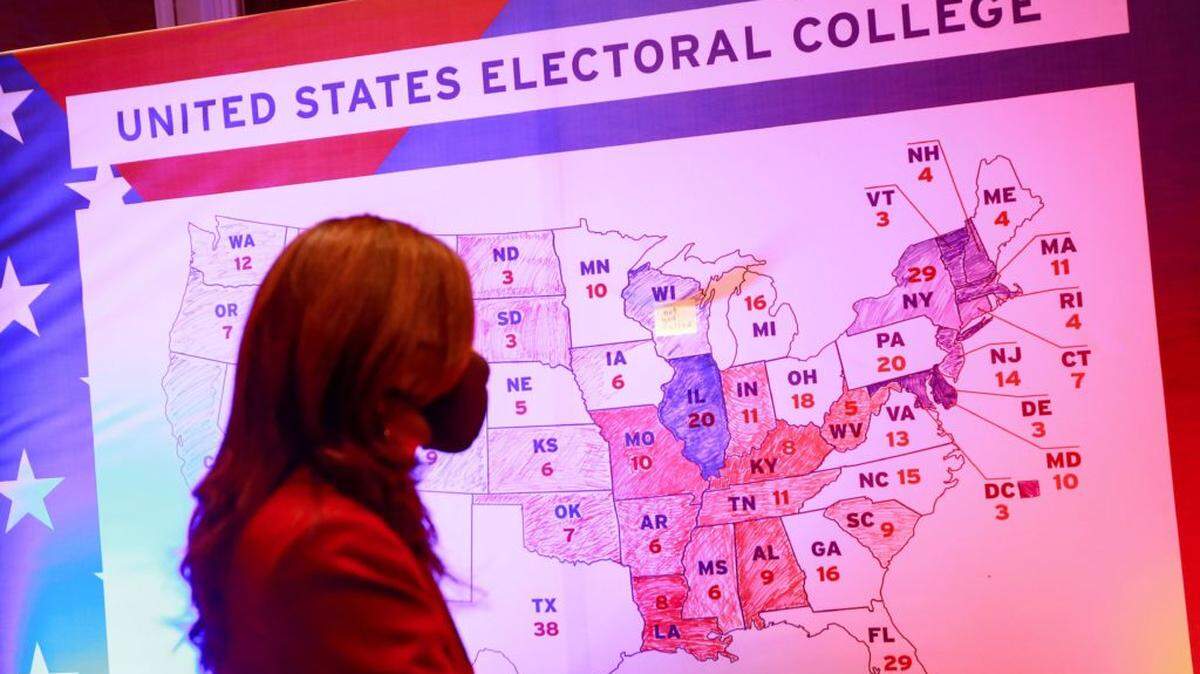A woman walks past an electoral map during a US presidential election watch party at the US embassy in Ulaanbaatar, the capital of Mongolia on November 4, 2020. (Photo by Byambasuren BYAMBA-OCHIR / AFP) (Photo by BYAMBASUREN BYAMBA-OCHIR/AFP via Getty Images)
