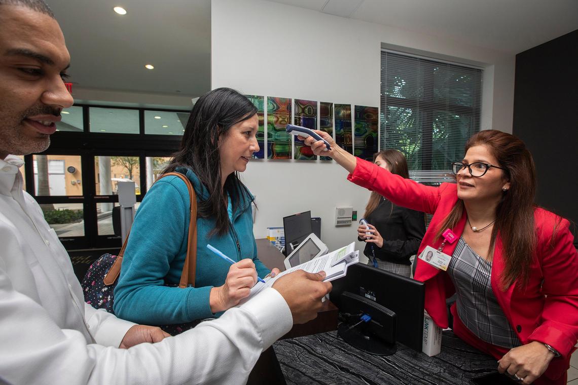 Employee, Beatriz Hernández get her temperature by Yamile Rivero RN BSN Director of nursing University Plaza when patients, visitors and staff enter at the building University Plaza Rehabilitation and Nursing in Miami on Monday March 9th., 2020. (L) Alan Solar, Administrator of Nursing University Plaza. This is for a story on how hospitals and nursing homes are trying to protect their patients and their staffs from the coronavirus.