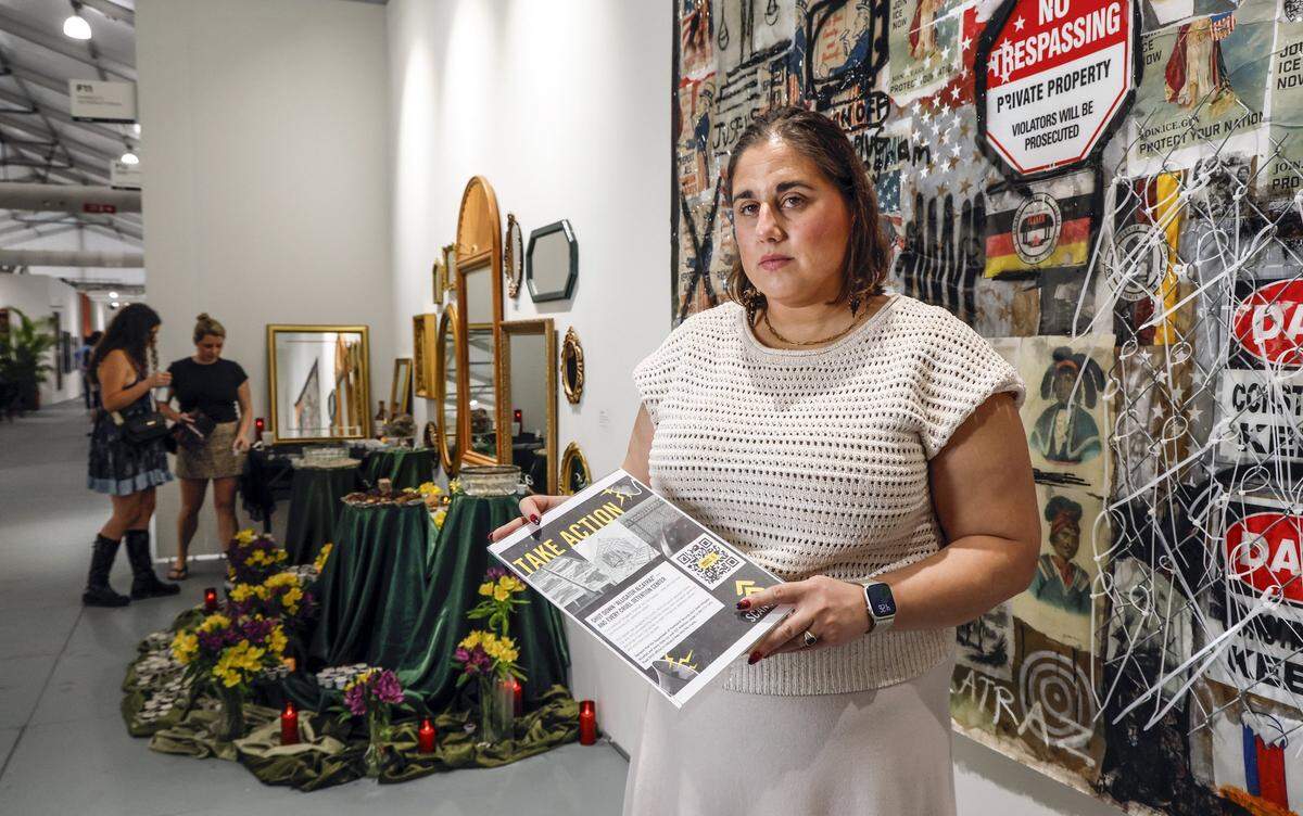 Amy Fischer, Director of Refugee and Migrant Rights for Amnesty International stands at the installation at this week's SCOPE Art Show protesting the Alligator Alcatraz immigration detention center in the Florida Everglades. The work by Clarence James and Agua Dullce is set amid the fair's international art displays at the SCOPE Pavilion on Miami Beach, Florida, on Wednesday, December 3, 2025. 