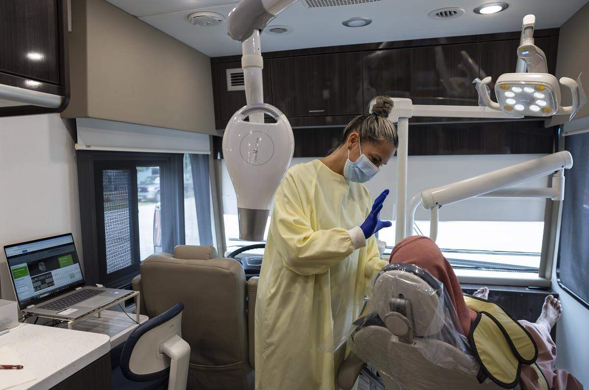 Yadira Mesa, a dental assistant with Caring for Miami, takes X-rays of Khurshida Jahan’s teeth inside the Mobile Dental Clinic.. Caring for Miami  and UHI CommunityCare Clinic are providing free dental care  for underserved residents in Opa-Locka.