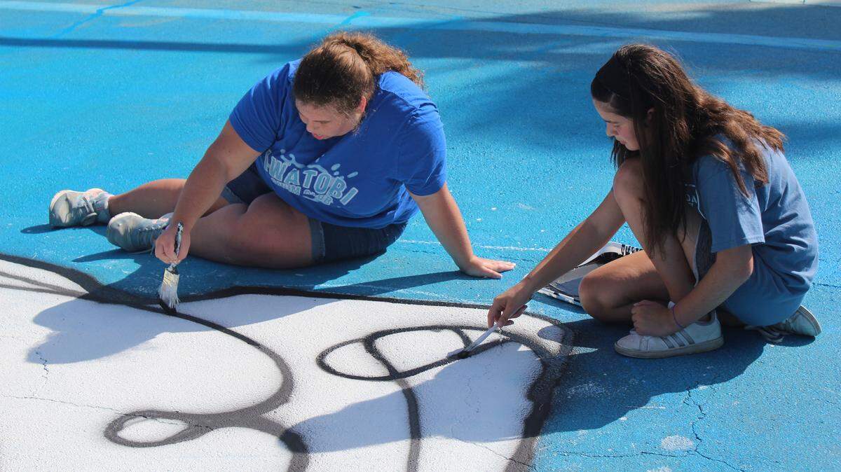Alison Keepax and Maria Sofia Latour of Gulliver Preparatory School work to paint an underwater marker for one of the streets on Killian Drive in Miami. Students from Gulliver, Michael Krop High School, South Dade High School and Westminster Christian School worked with Xavier Cortada, a local environmental artist, to create underwater markers for the Underwater Homeowners Association’s sea level rise initiative.