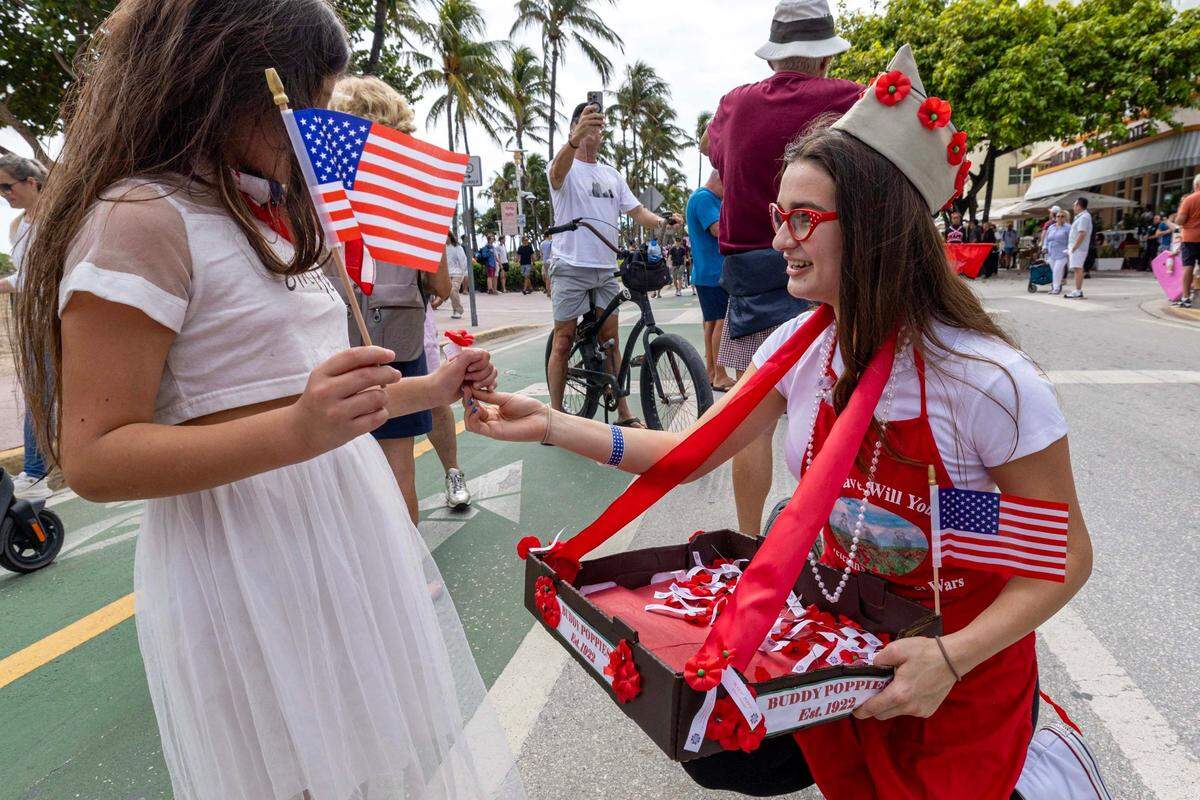 Aubrey from Girl Scout Troop 1239 hands out a ‘Buddy Poppey’ to a young girl during the 16th Annual Veterans Day Parade off Ocean Drive on Monday, Nov. 11, 2024, in Miami Beach, Fla.