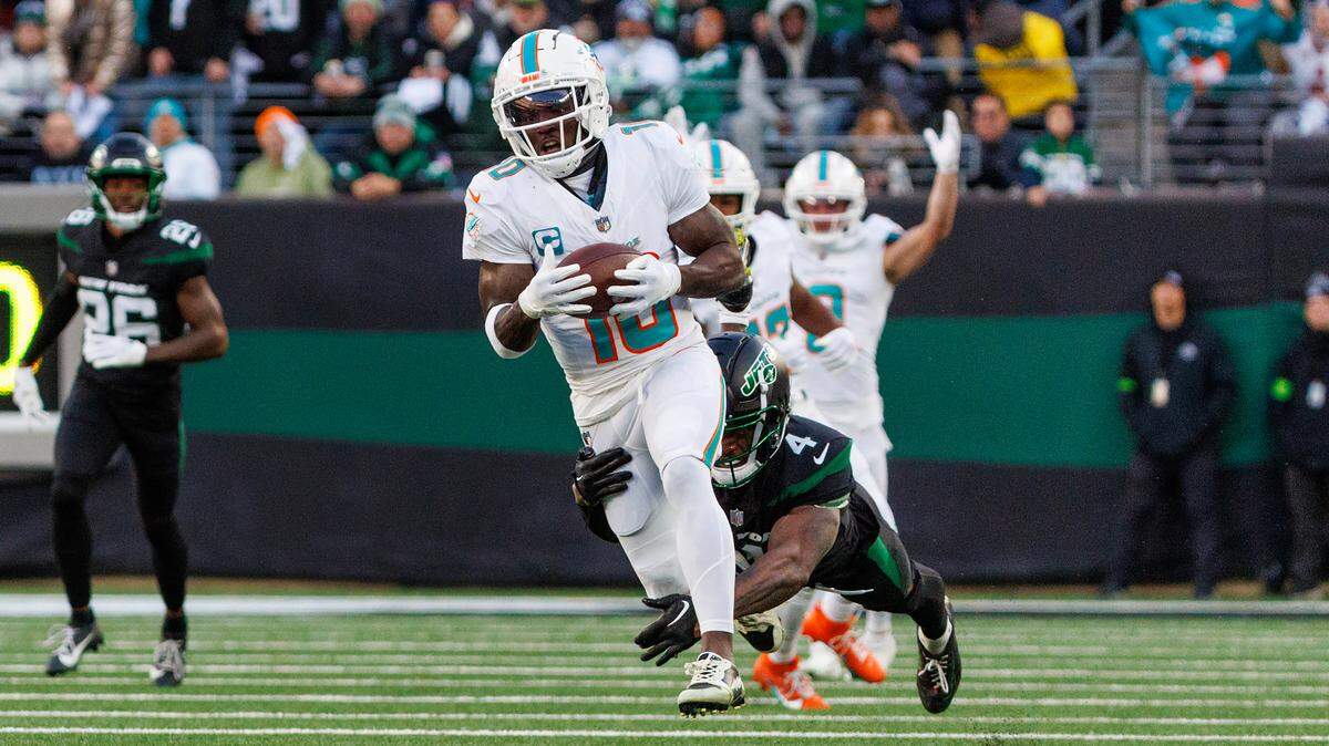 Miami Dolphins wide receiver Tyreek Hill (10) runs with the football as New York Jets cornerback D.J. Reed (4) defends during first quarter of an NFL football game at MetLife Stadium on Friday, Nov. 24, 2023 in East Rutherford, New Jersey.