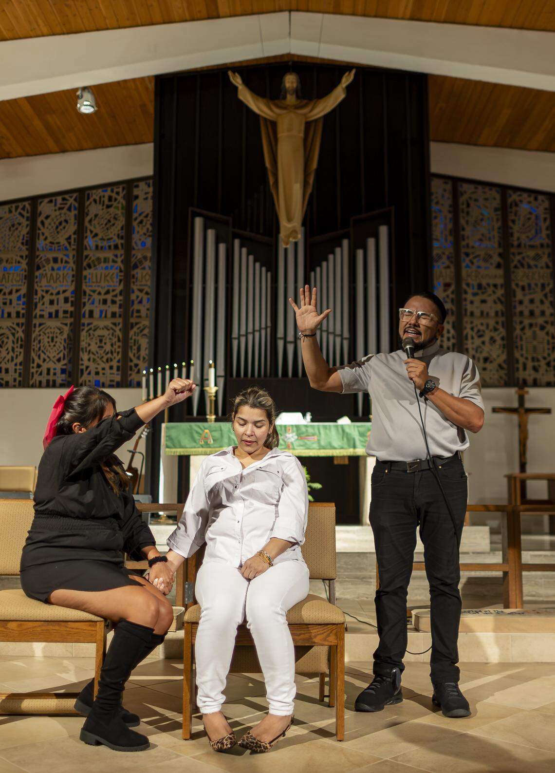 Pastor Oscar Restrepo, right, and Yiralit Vanegas, left, pray for Laura during a vigil at Christ Lutheran Church on Saturday, Aug. 9, 2025, in Oakland Park, Fla. Laura, who is undocumented, has a 13-year-old son and was recently diagnosed with terminal cancer, watched two months ago as her husband, Luis, was detained by ICE and taken to a detention center in Louisiana. The vigil brought together immigrant families and others supporting loved ones in migrant detention centers, such as Alligator Alcatraz, across the state and country.