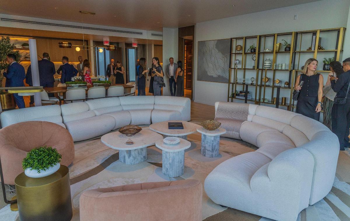 Guests check the model living room of an apartment at the Mandarin Residences sales center during a hotel closing party on Thursday May 15, 2025. .