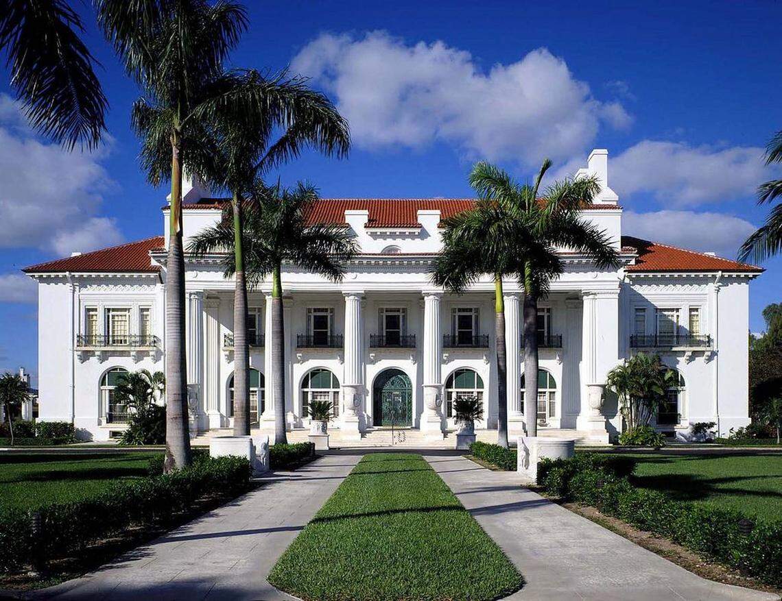 The front facade of Whitehall, Henry Flagler's Gilded Age estate, features white columns, a terracotta tile roof and lush palm trees.