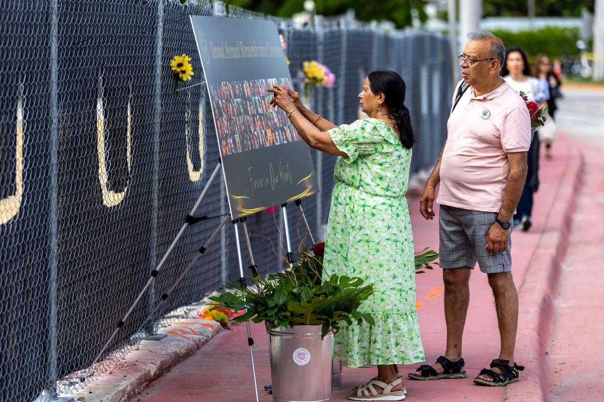 Kishore Parekh, right, and Purnima Parekh, left, interact with a poster with pictures of the 98 lives lost during the Champlain Towers South building collapse on June 24, 2021, before the Second Annual Rememberance Ceremonny of the incident at Veterans Park on Saturday, June 24, 2023, in Surfside, Florida. The Parekh family lost their daughter Bhavna Patel, 38, along with their son-in-law Vishal Patel , 42, and their 1-year-old grand daughter Aishani.