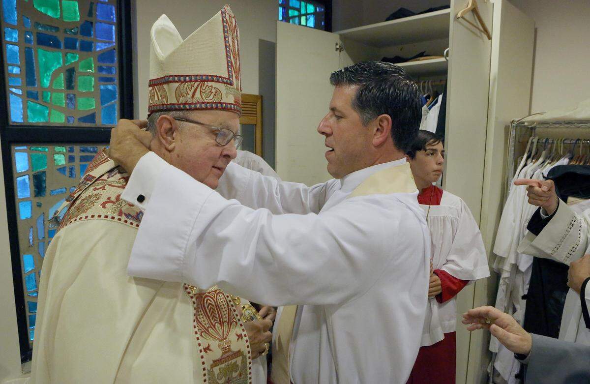 The Rev. Alberto Cutié arranges the vestments of Bishop Leo Frade, the Episcopal bishop of Southeast Florida, on May 13, 2015, when Cutié became the new rector of St. Benedict’s Episcopal Church in Plantation. 