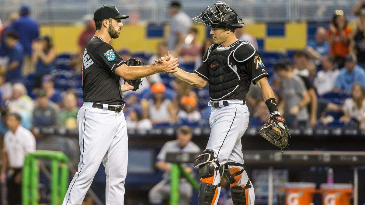 Miami Marlins relief pitcher Kyle Barraclough (46) and Marlins catcher J.T. Realmuto celebrate the 5-2 victory over the Mets at Marlins Park in Miami, Saturday, June 30, 2018.
