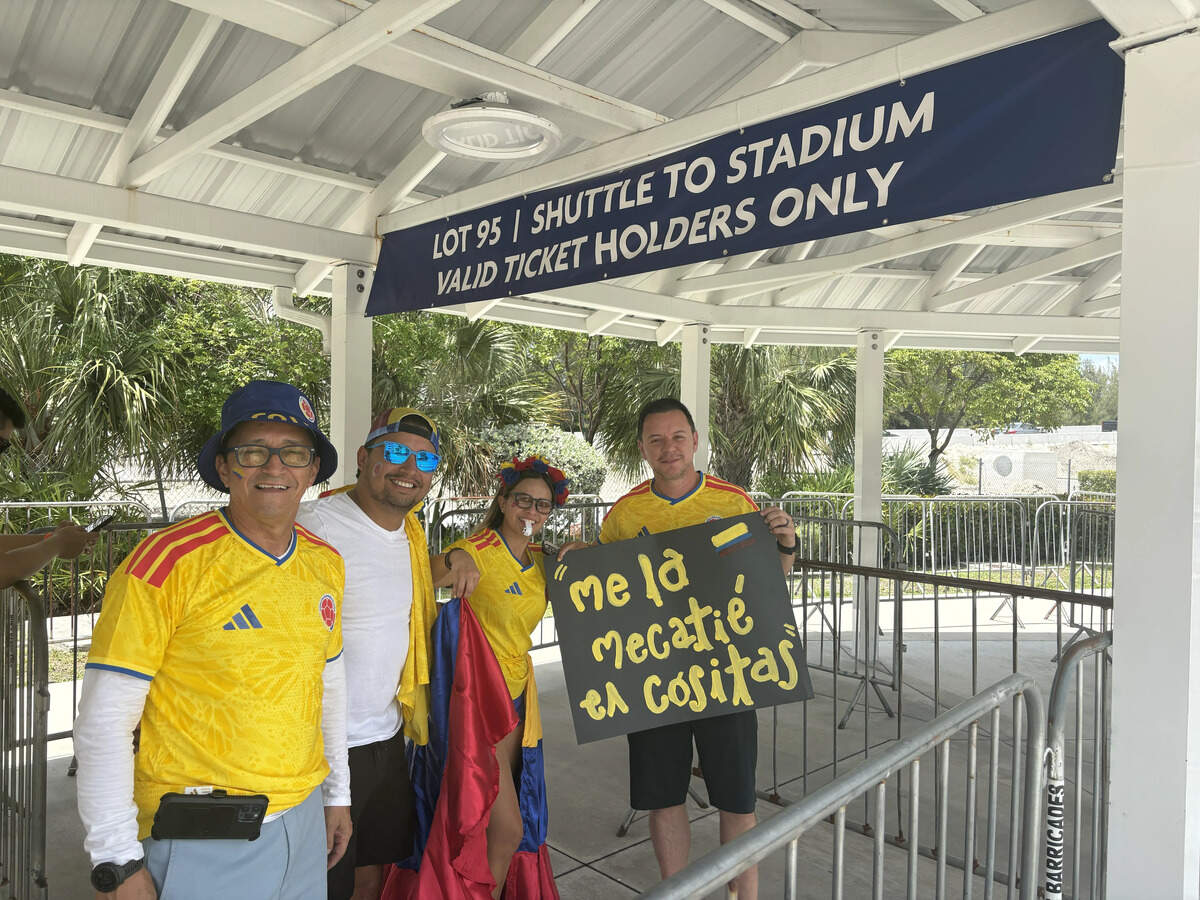 Left to right: Jose Ladino, Andrey Ladino, Gyna Parrado, Julian Calero. Native Colombians who now live in South Florida, the crew showed up to the Golden Glades transit hub hours before the first shuttle was due. Passage on the shuttle requires a ticket, and Andrey Ladino said his cost $1,600. Calero holds a sign that he said loosely translates to: “I spent all my money.”