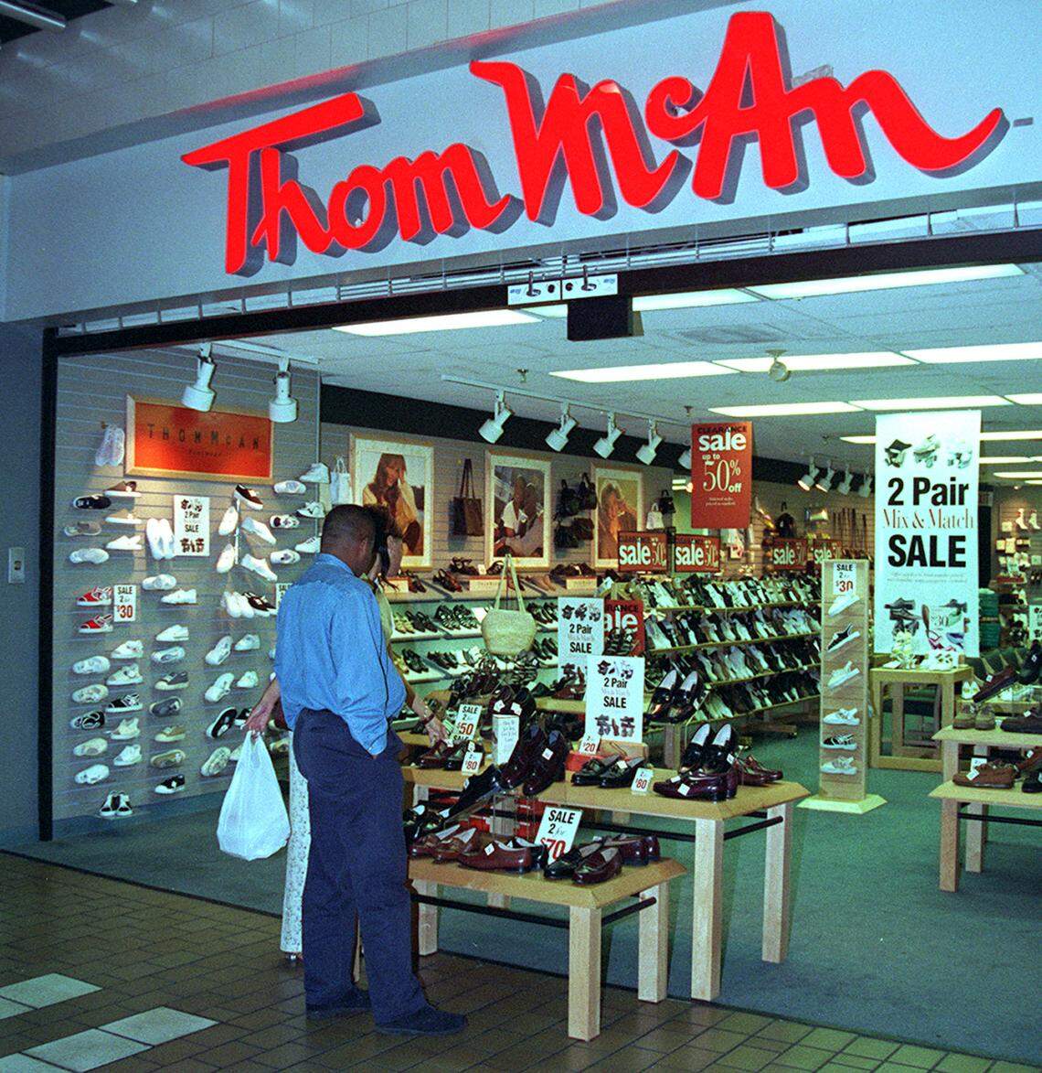 A shopper stands outside the closing Thom McAn Shoe Store inside the Omni International Mall.