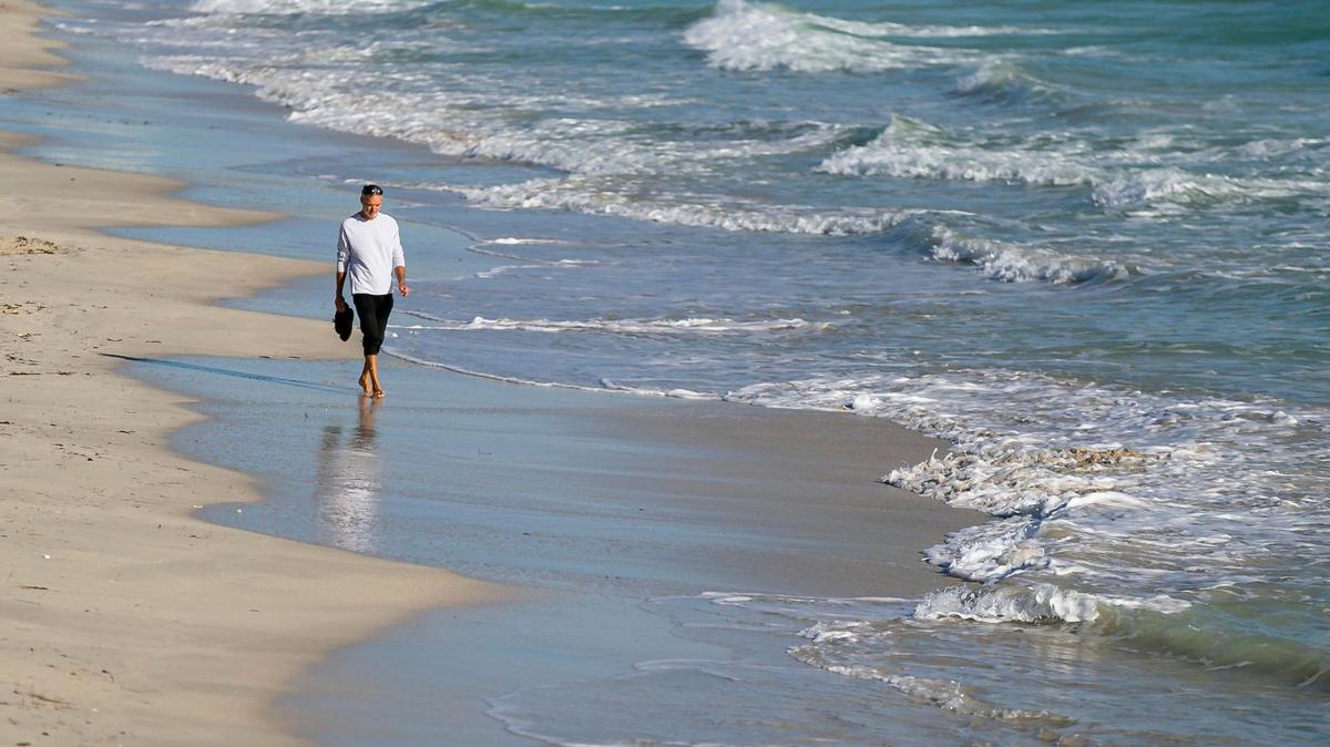 A man makes his way down the Miami Beach coastline near South Pointe Park Pier after temperatures dipped into the mid-50s and low 60s across South Florida on Wednesday, Dec. 2, 2020.