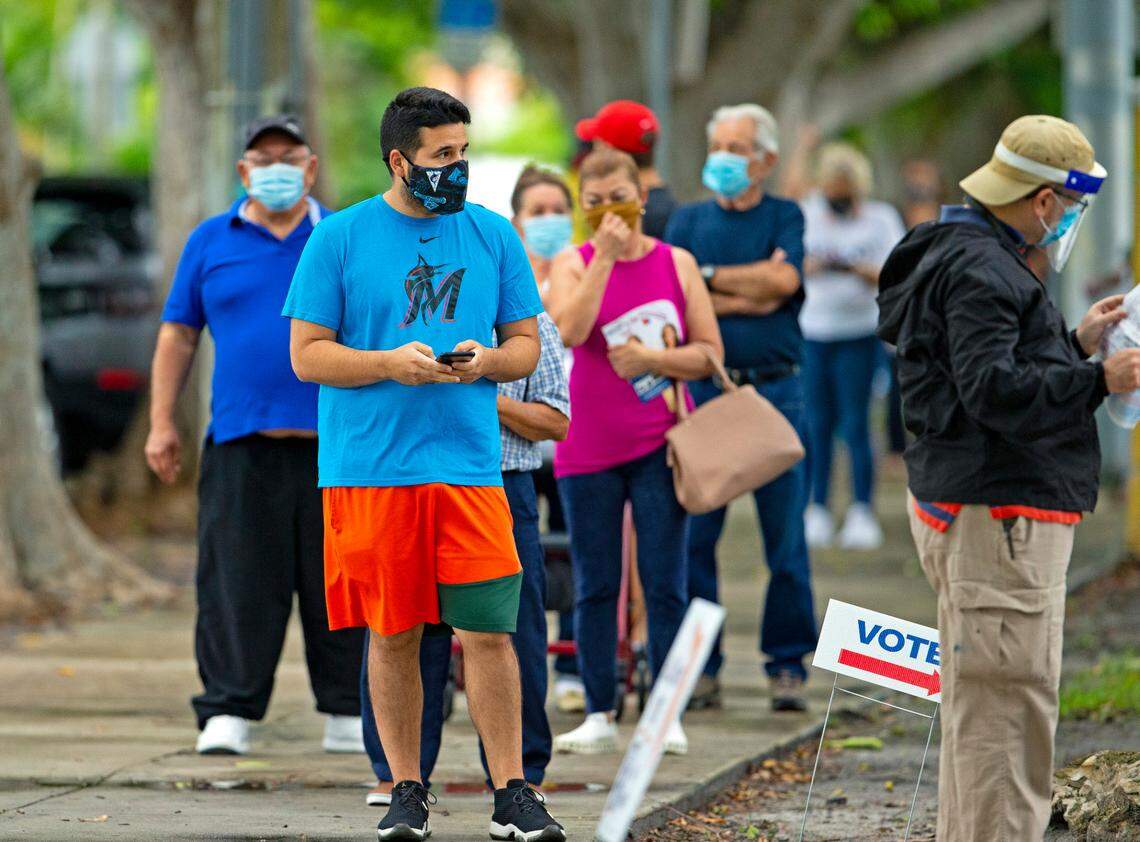 People stand in line to vote on the first day of early voting for the general election at Shenandoah Branch Library at 2111 SW 19th St. on Monday, October 19, 2020, in Miami, Florida.