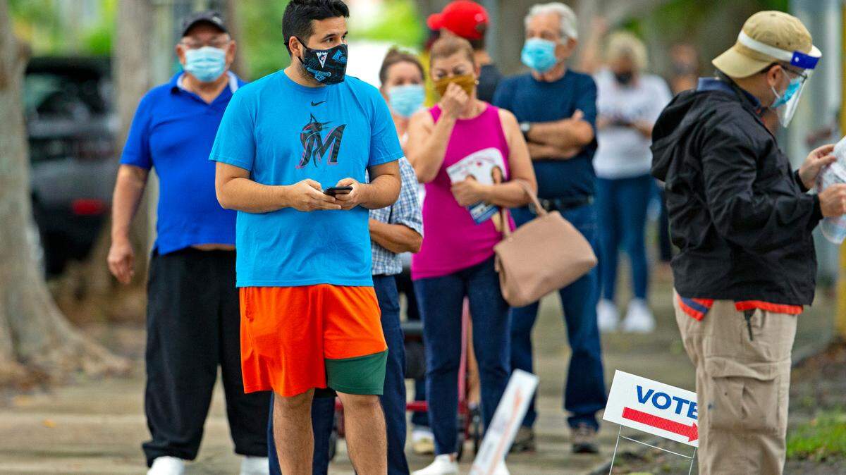 People stand on line to vote on first day of early voting for the general election at Shenandoah Branch Library located at 2111 SW 19th St. on Monday, October 19, 2020, in Miami, Florida.