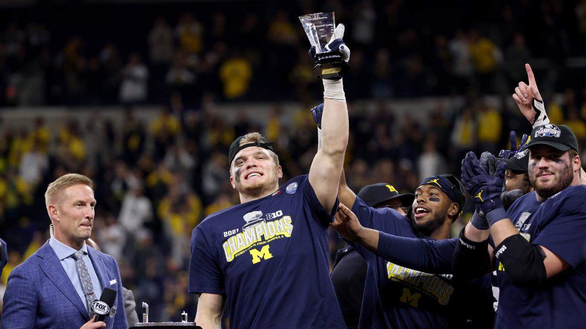 Aidan Hutchinson #97 of the Michigan Wolverines celebrates on the podium after being named the MVP of the Big Ten Championship game against the Iowa Hawkeyes at Lucas Oil Stadium on December 04, 2021 in Indianapolis, Indiana.