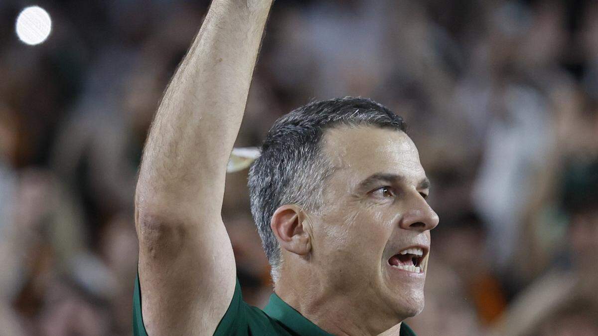 Miami Hurricanes head coach Mario Cristobal raises the diamond-encrusted football that is fully removable from the Fiesta Bowl Trophy, as the team celebrates on stage after defeating the Mississippi Rebels in the College Football Playoff semifinal at the Fiesta Bowl at State Farm Stadium on Friday, January 9, 2026 in Glendale, Arizona. 