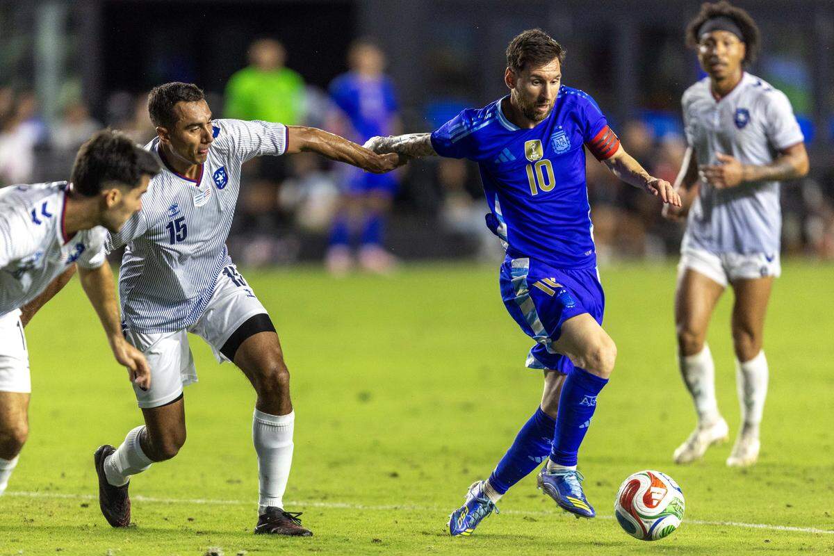 Argentina forward Lionel Messi (10) controls the ball while pulled by Puerto Rico left back Gio Calderón during the second half of an international team friendly at Chase Stadium on Tuesday, October 14, 2025, in Fort Lauderdale, Fla.