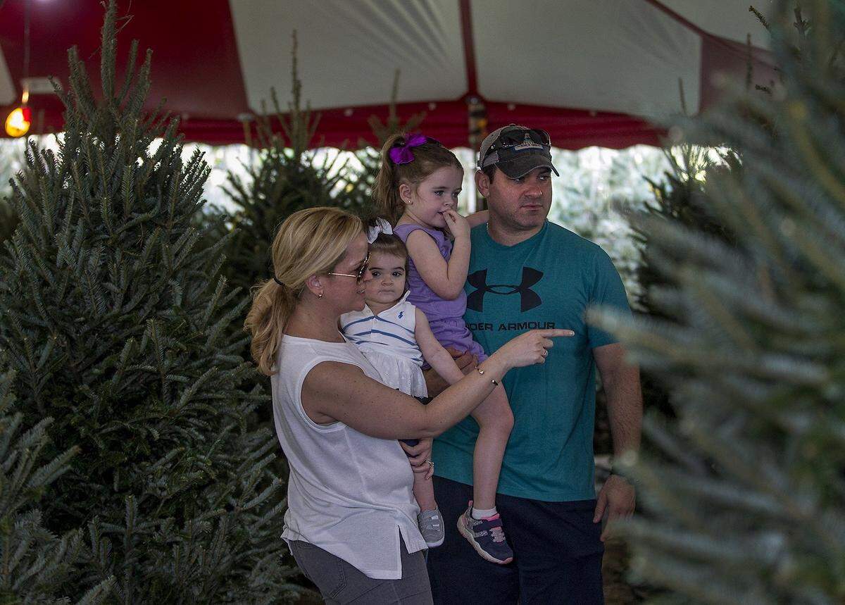 Annabel Lopez holds her 1-year-old daughter Autumn as husband Joseph Lopez holds 4-year-old Avery while choosing the perfect Christmas tree at the Boys and Girls Clubs of Miami in 2018.