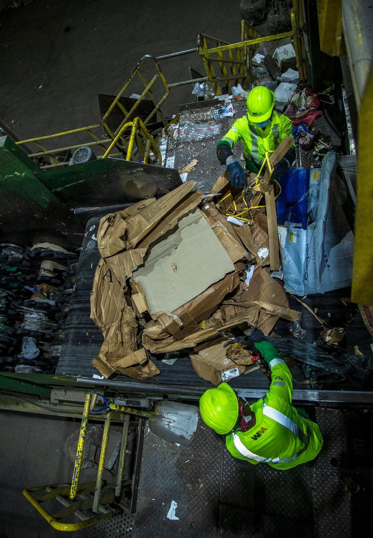 Workers sort out recycled materials, including cardboard and paper, on a conveyor at the Waste Management Recycling Plant at 20701 Pembroke Road in Pembroke Pines, Florida, on April 8, 2022.
