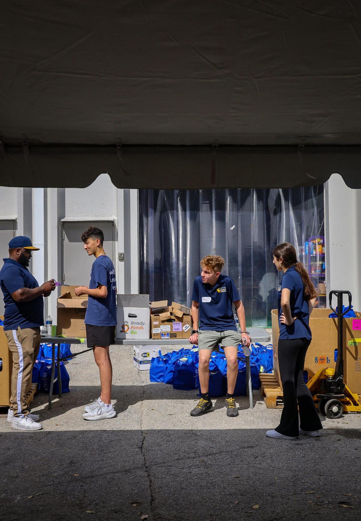 Warehouse manager Montrese Wilson, left, talks with volunteers - David Maratchi, 15, David Marcovitz, 17, and Zoe Avinir, 17, right, during a short break in deliveries.